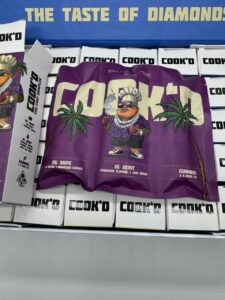 COOK'D 2G disposable vape, 1G pre-roll joint, and three THC gummies Juiced Edition cannabis bundle branded packaging.